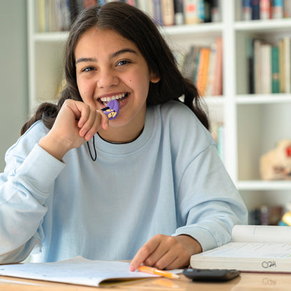 Young adult chews on purple fox oral motor aid with a neck lanyard