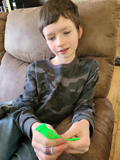 Boy plays with green mesh stimming toy