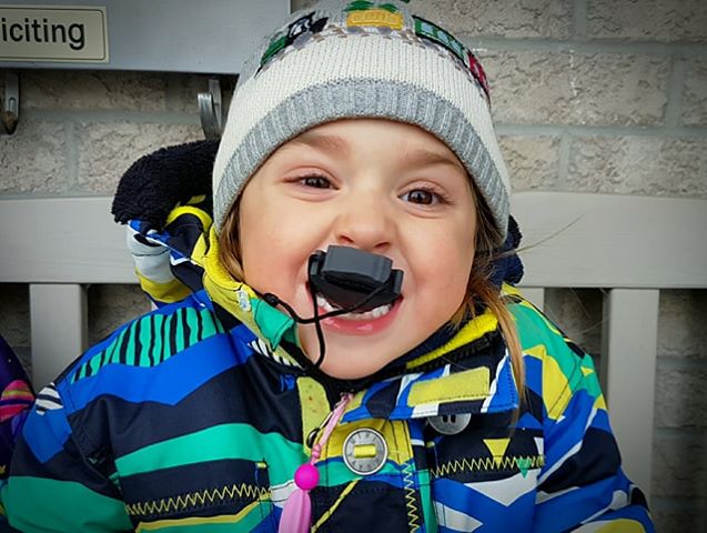 Young boy chews on Arrowhead chewable jewelry. Also wears a chewable zipper pull.